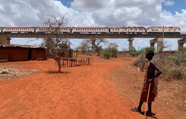 A young man watches a Standard Gauge Railway passenger train zoom over his home in Taita Taveta county, south-eastern Kenya.
Author provided