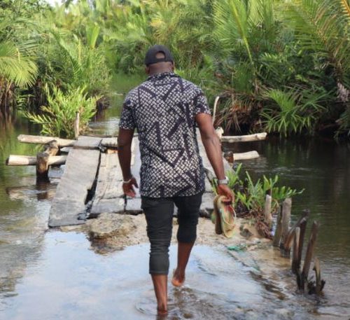 Ezekiel Robert, chairman of the Okwan Obolo community of the Emere-oke kingdom, walks on a flooded bridge. Credit: Ekpali Saint.