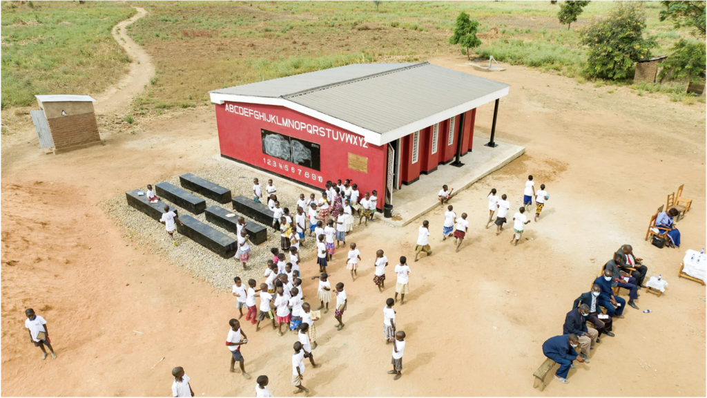 a 3d printed school in Malawi with children playing outside